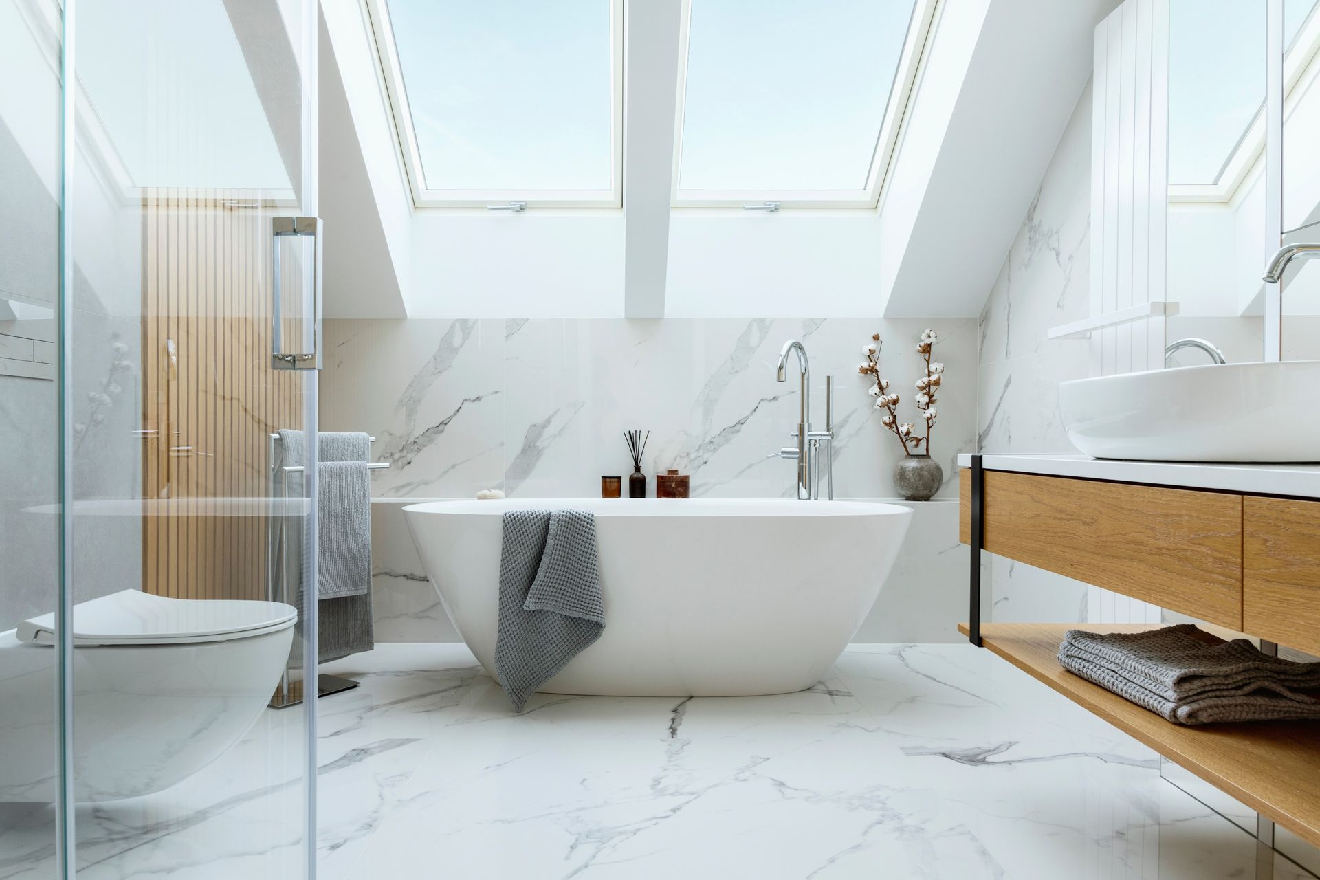 A bathroom with a bathtub , sink , toilet and skylight.