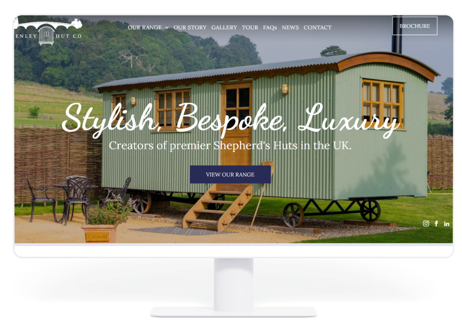 A desktop monitor displays a website for luxury shepherd's huts, featuring a light green hut in a rural garden setting.