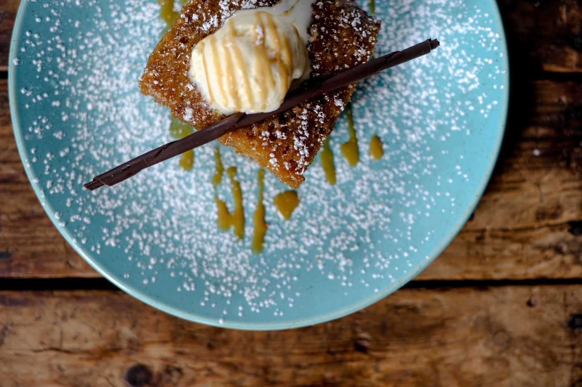 A blue plate topped with a dessert and ice cream on a wooden table.
