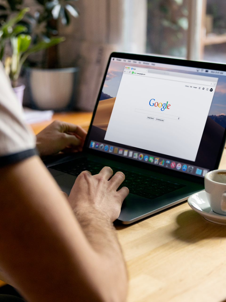 A man is sitting at a table using a laptop computer.