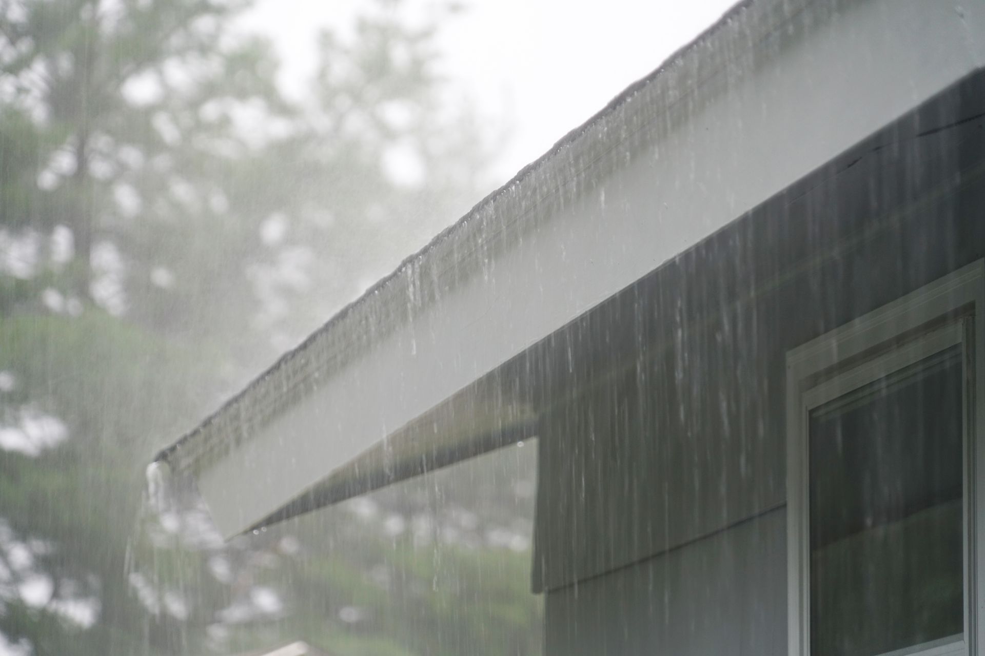 It is raining on the roof of a house.