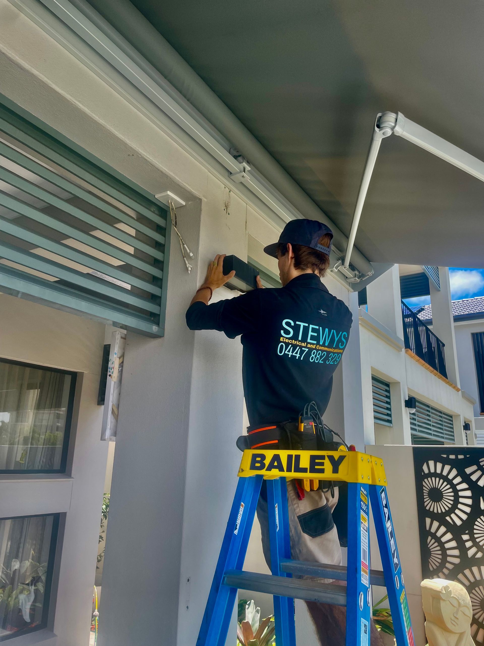 A Man is Standing in Front of a Truck on the Side of the Road — Stewys Electrical and Communications In Casuarina, NSW
