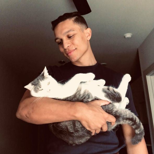 A man in a black shirt is holding a cat in his arms