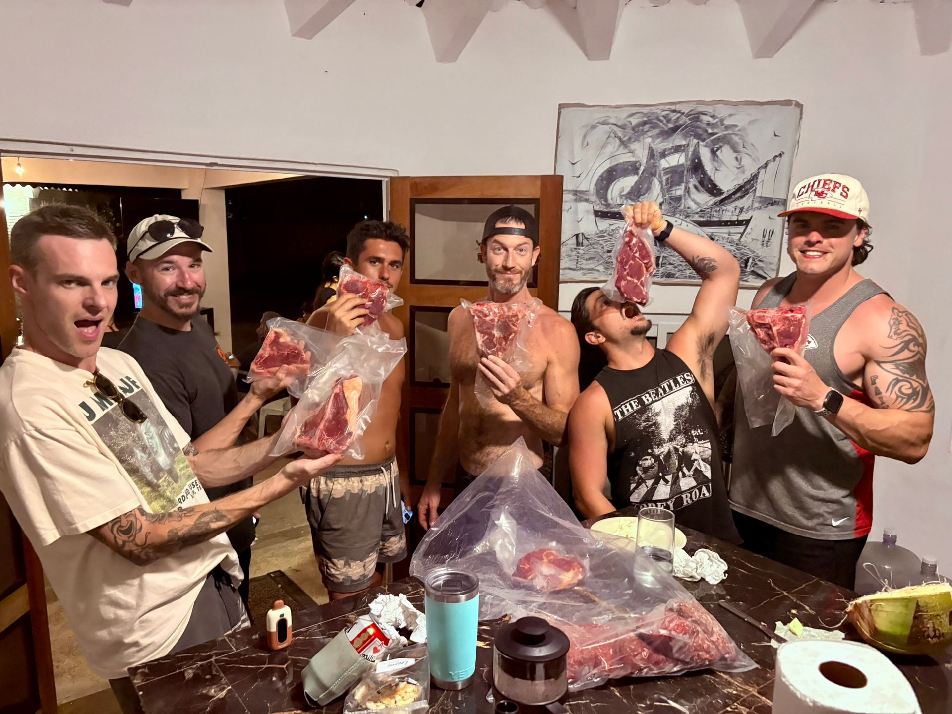 A group of men are standing around a table holding bags of meat.