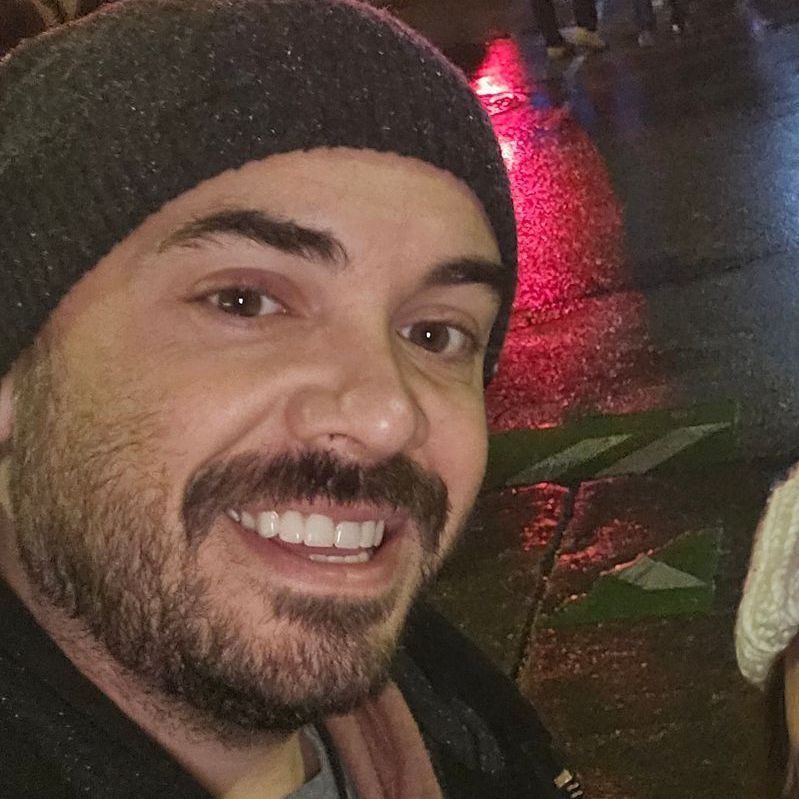 A man with a beard and a beanie is smiling for the camera.