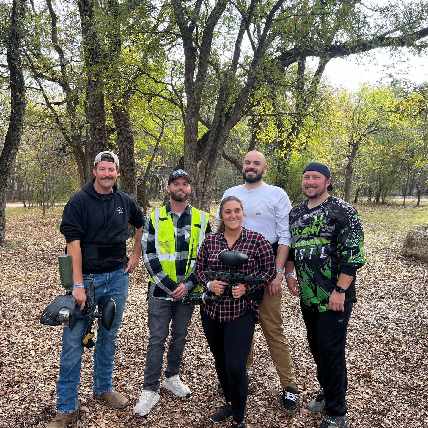 A group of people are posing for a picture in the woods.