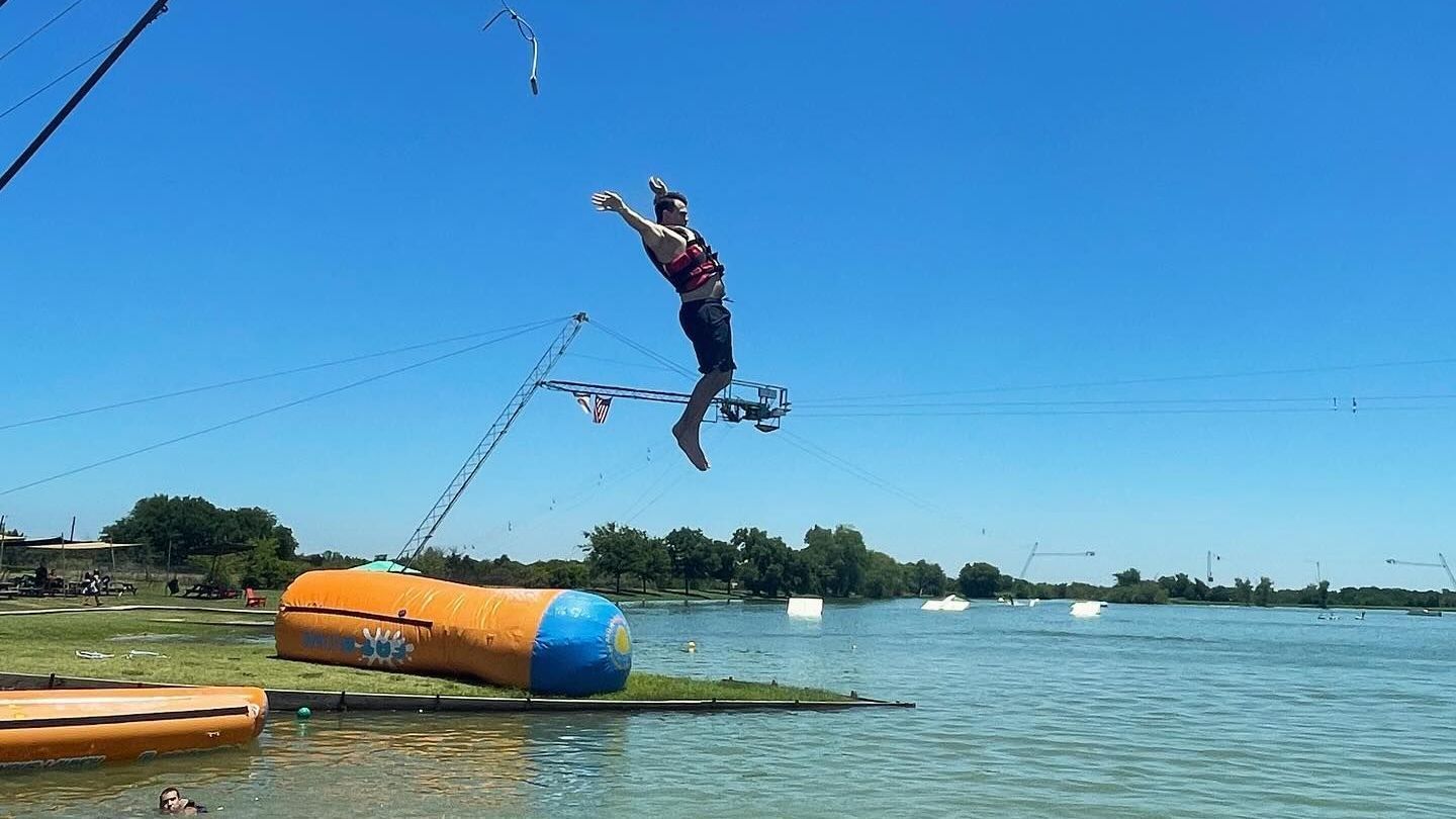 A man is jumping over a barrel in the water.