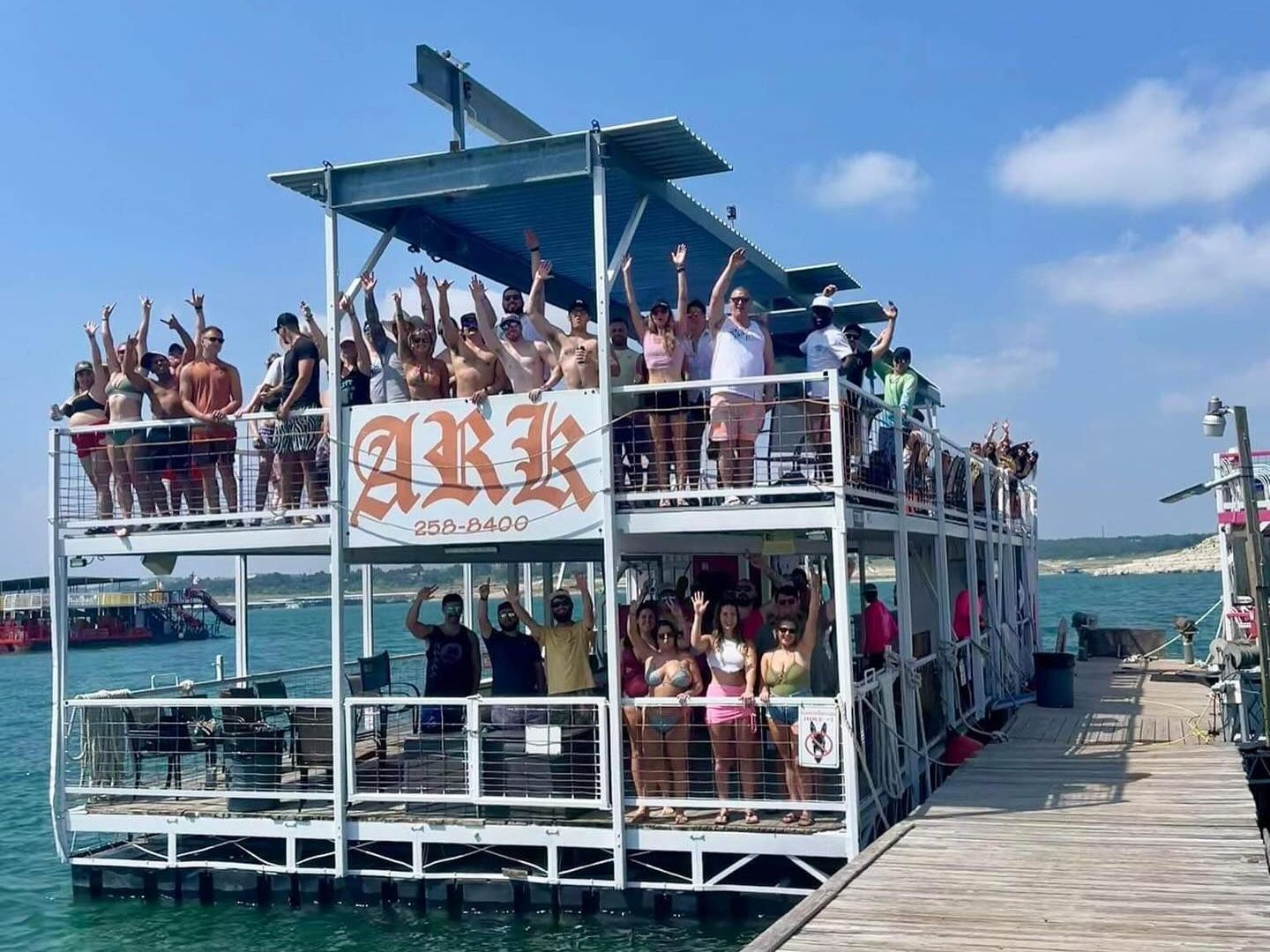 A group of people are standing on top of a boat in the water.