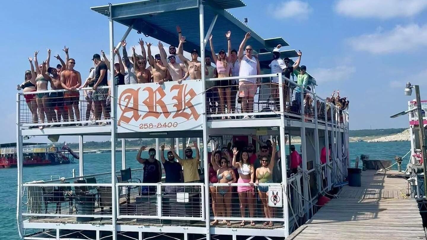A group of people are standing on top of a boat in the water.