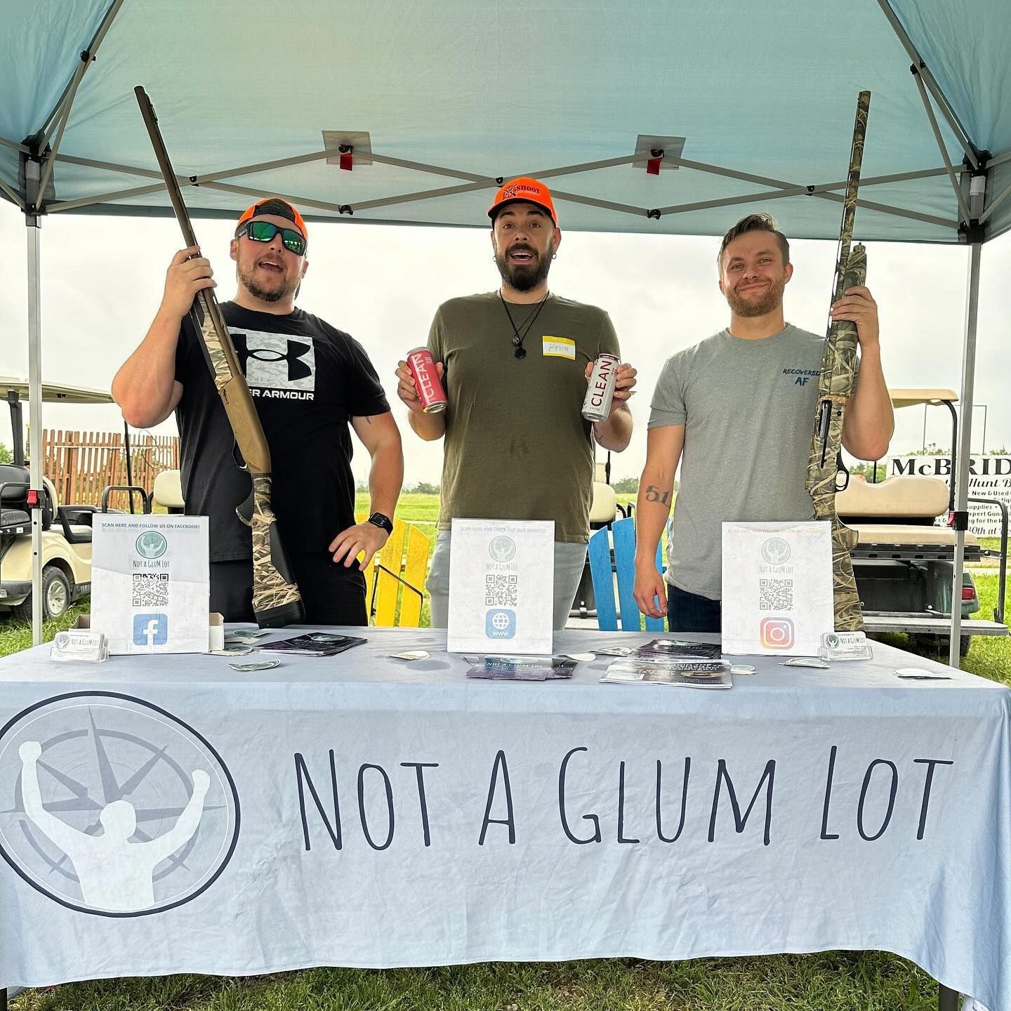 Three men standing behind a table that says not a glum lot