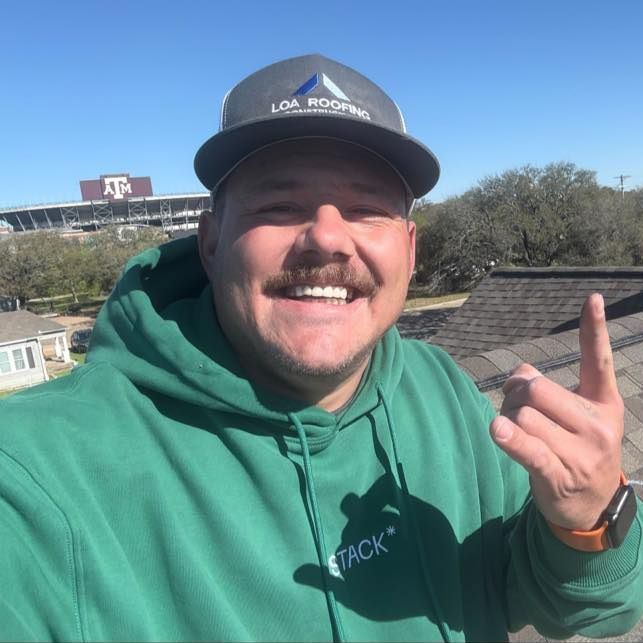 A man wearing a green hoodie and a black hat with the word roofing on it