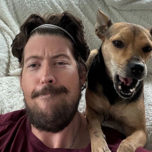 A man with a beard is posing for a picture with his dog