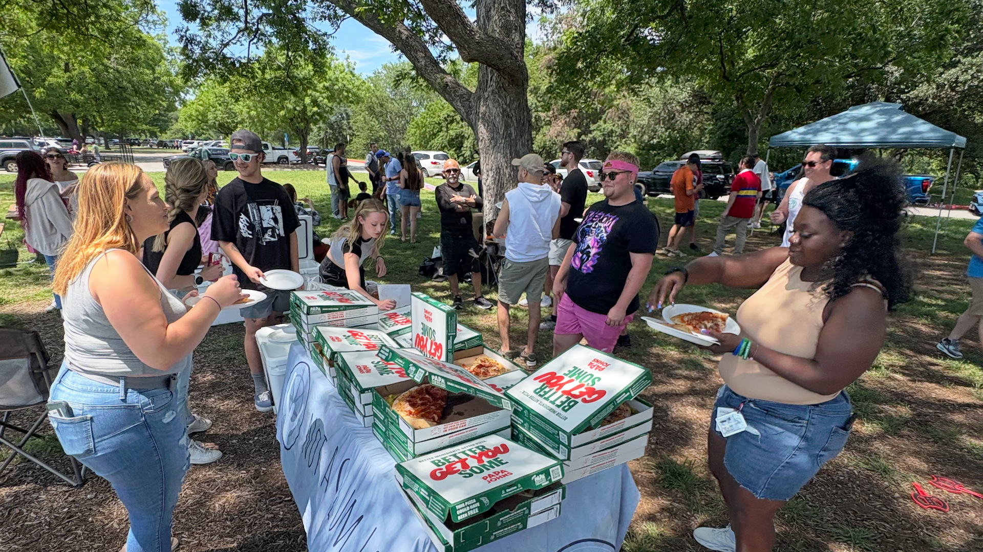 A group of people are eating pizza in a park.