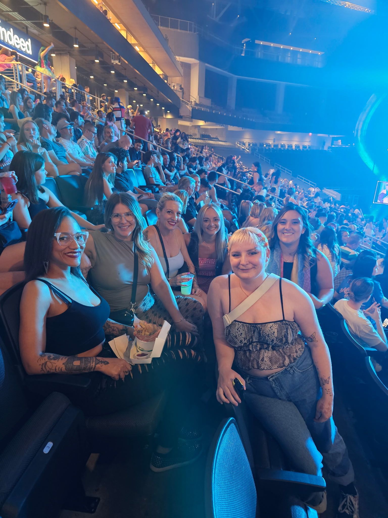 A group of women are sitting in a stadium watching a concert.