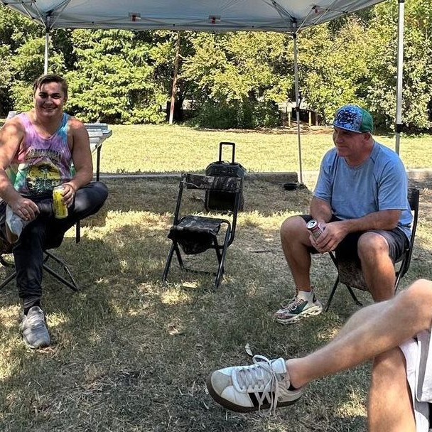Two men are playing a game at a picnic table in a park.