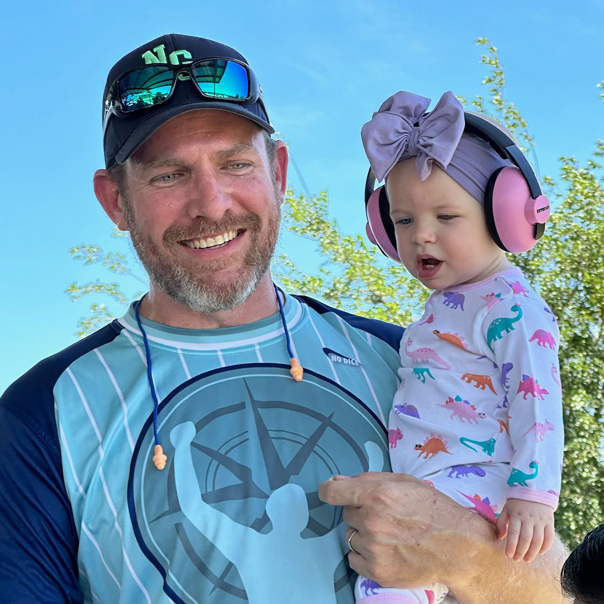 A man is holding a baby girl wearing headphones.