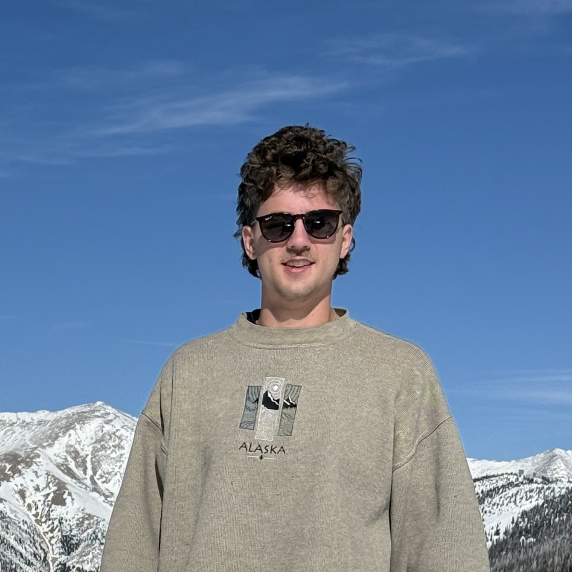 A man wearing sunglasses and a sweater that says alaska on it