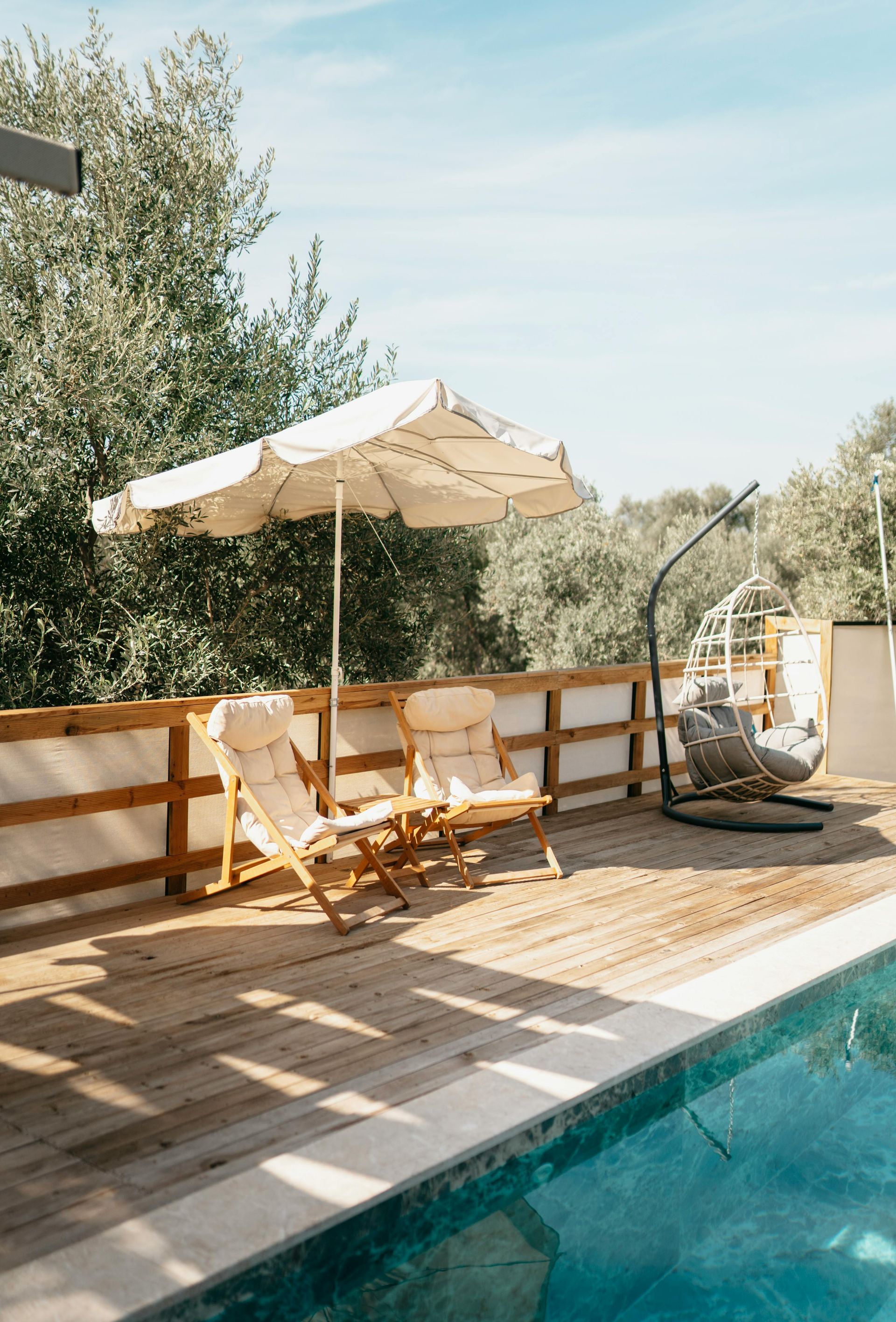 There is a swimming pool with chairs and umbrellas on the deck.