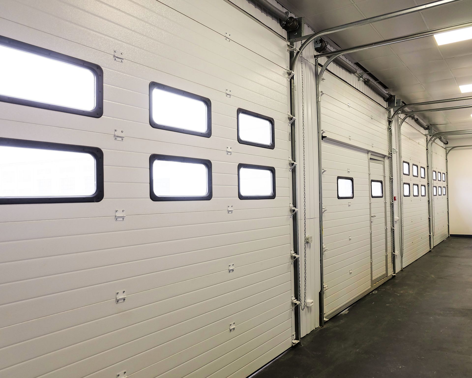 A row of white garage doors with square windows.