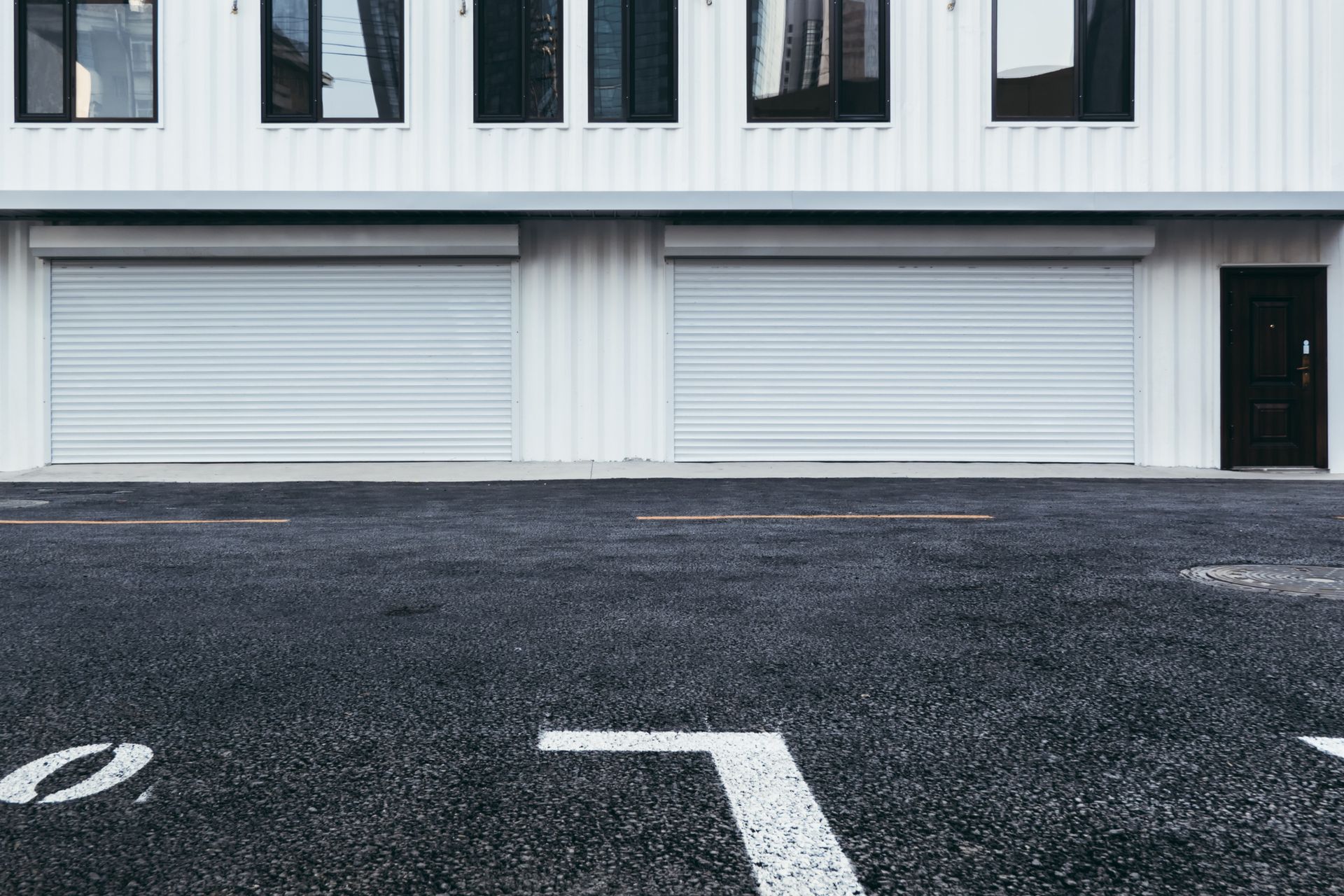 A black and white photo of a parking lot in front of a building.