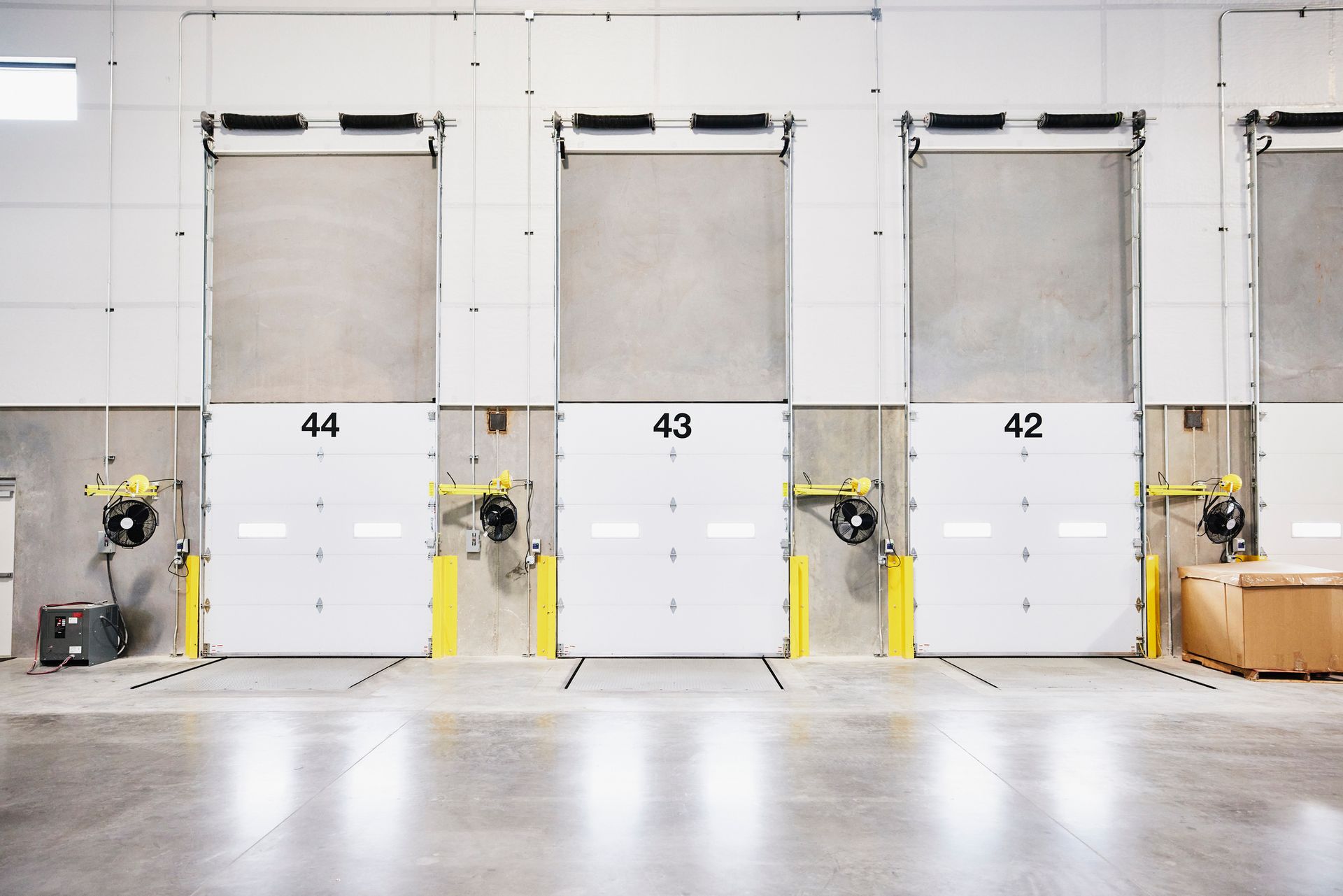 A row of white warehouse doors with the numbers 44, 43, and 42 on them.