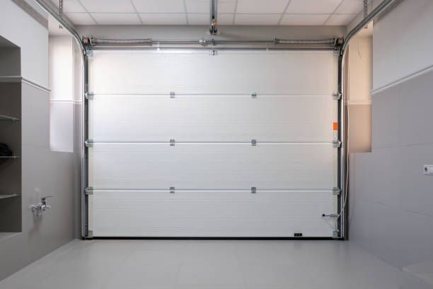 An empty garage with a white garage door open.