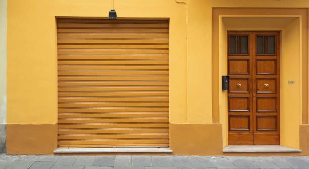 A yellow building with a wooden door and a yellow garage door.