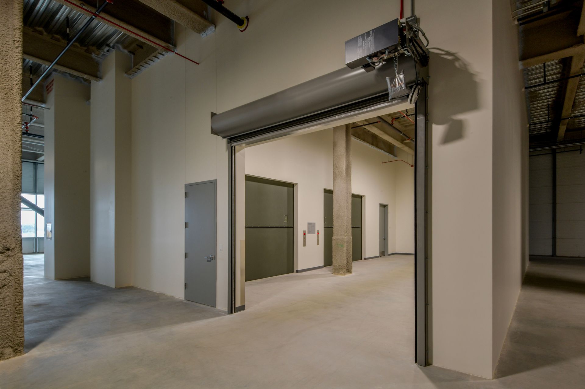 A large empty room with a roller shutter on the door.