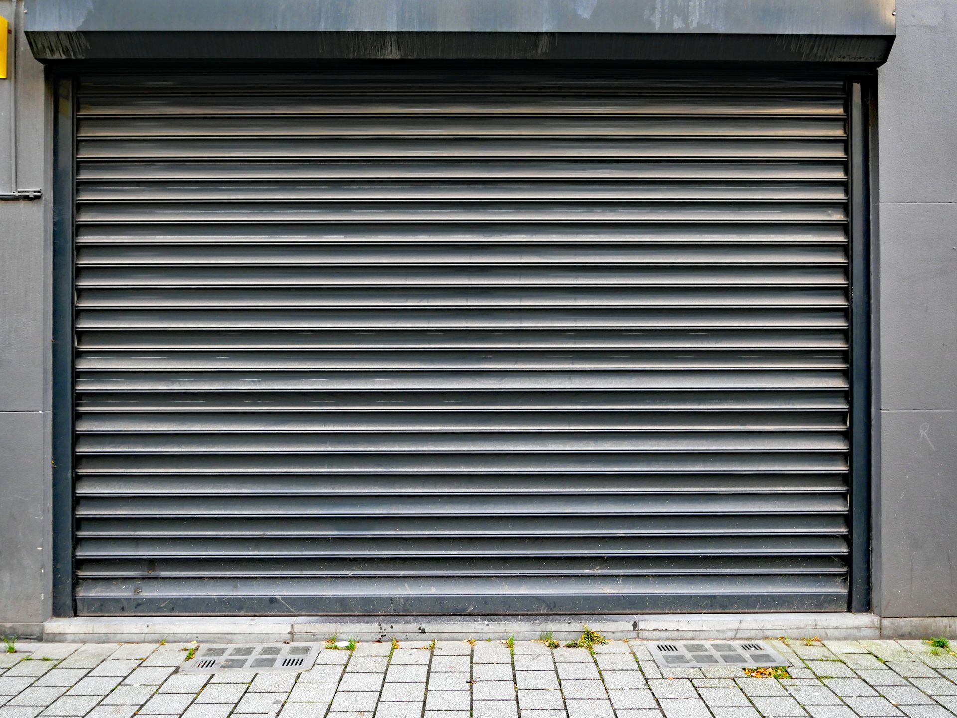 A close up of a garage door on a brick sidewalk.