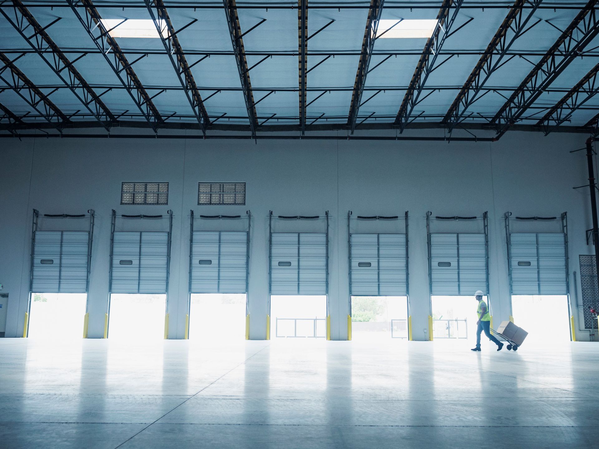A man is pushing a cart in a large warehouse.