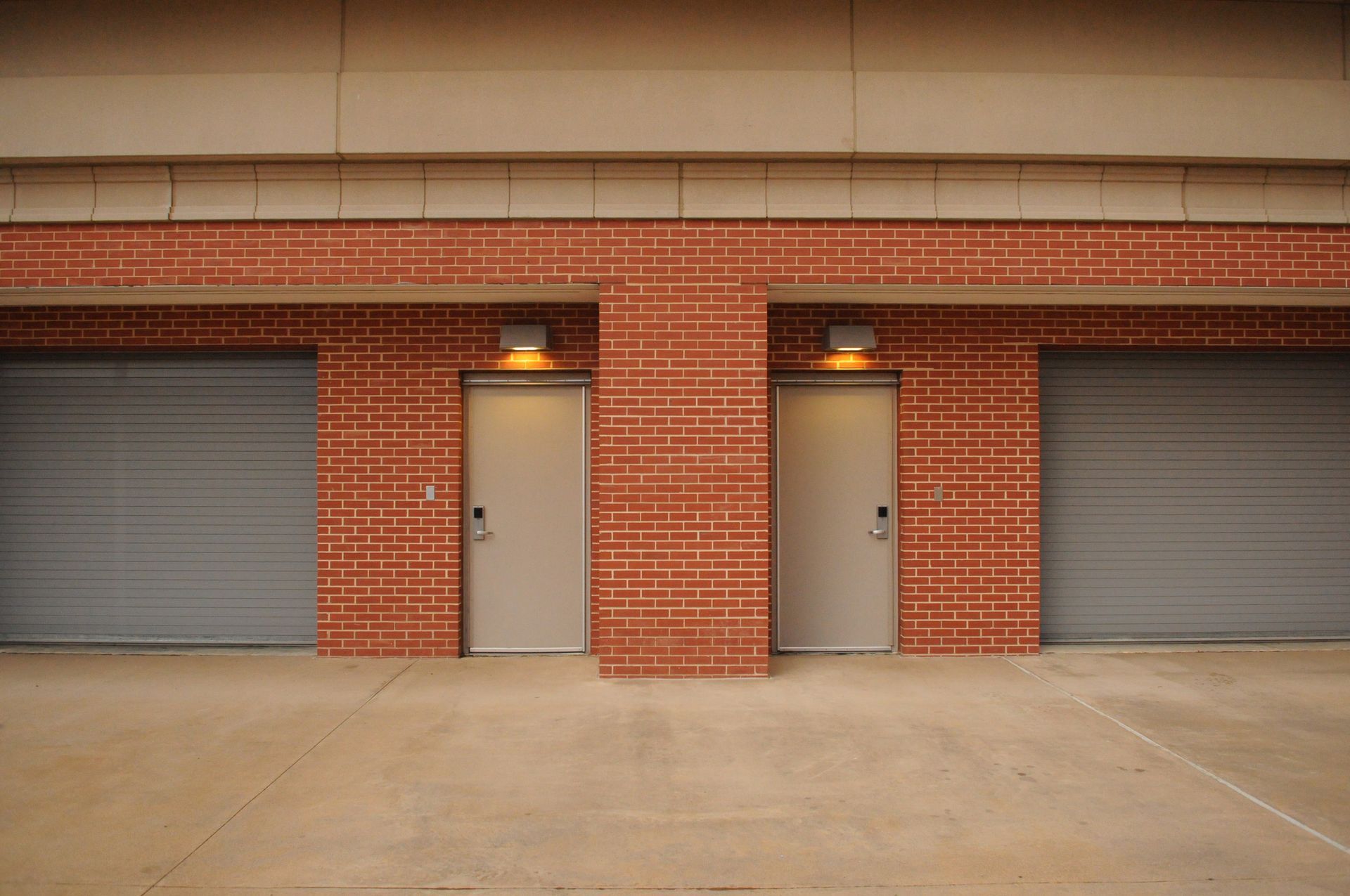 There are two garage doors on the side of a brick building.