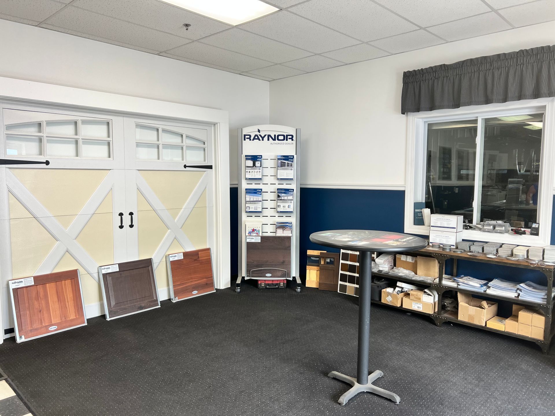 A room with a table and a display of garage doors.