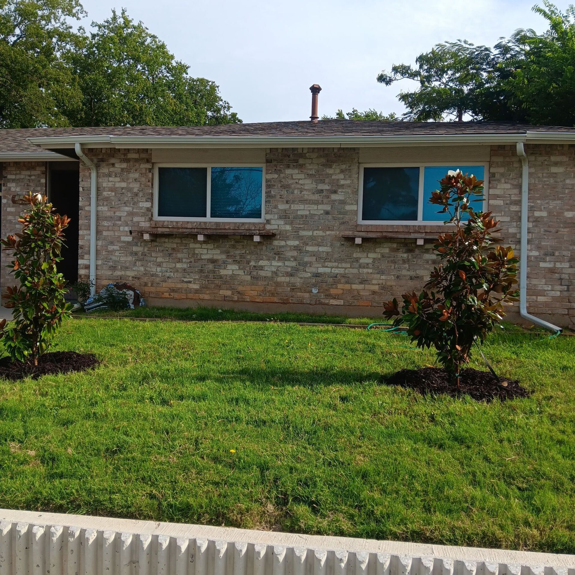 A brick house with a lush green lawn in front of it