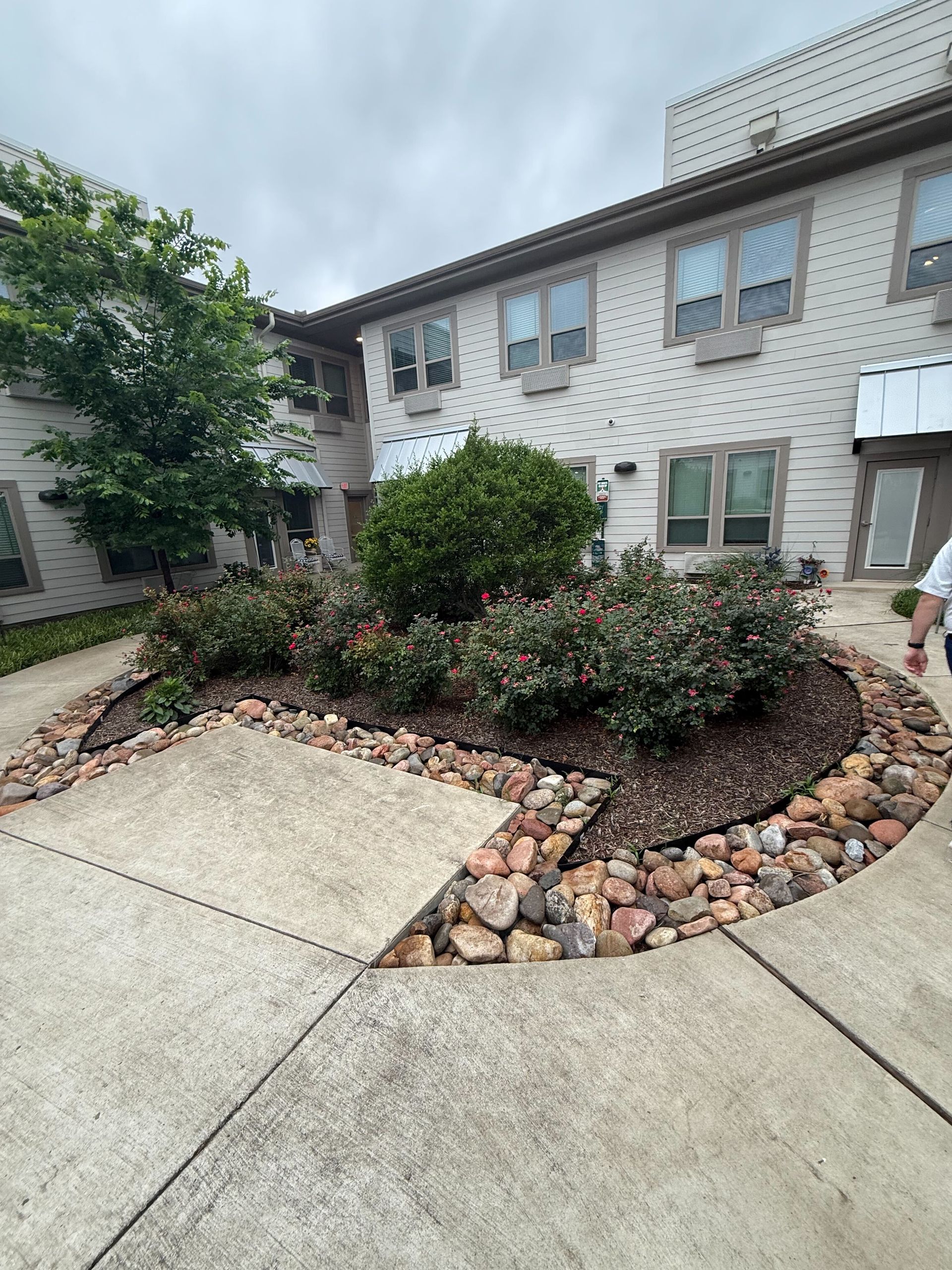 A man is standing in front of a building with a garden in front of it.