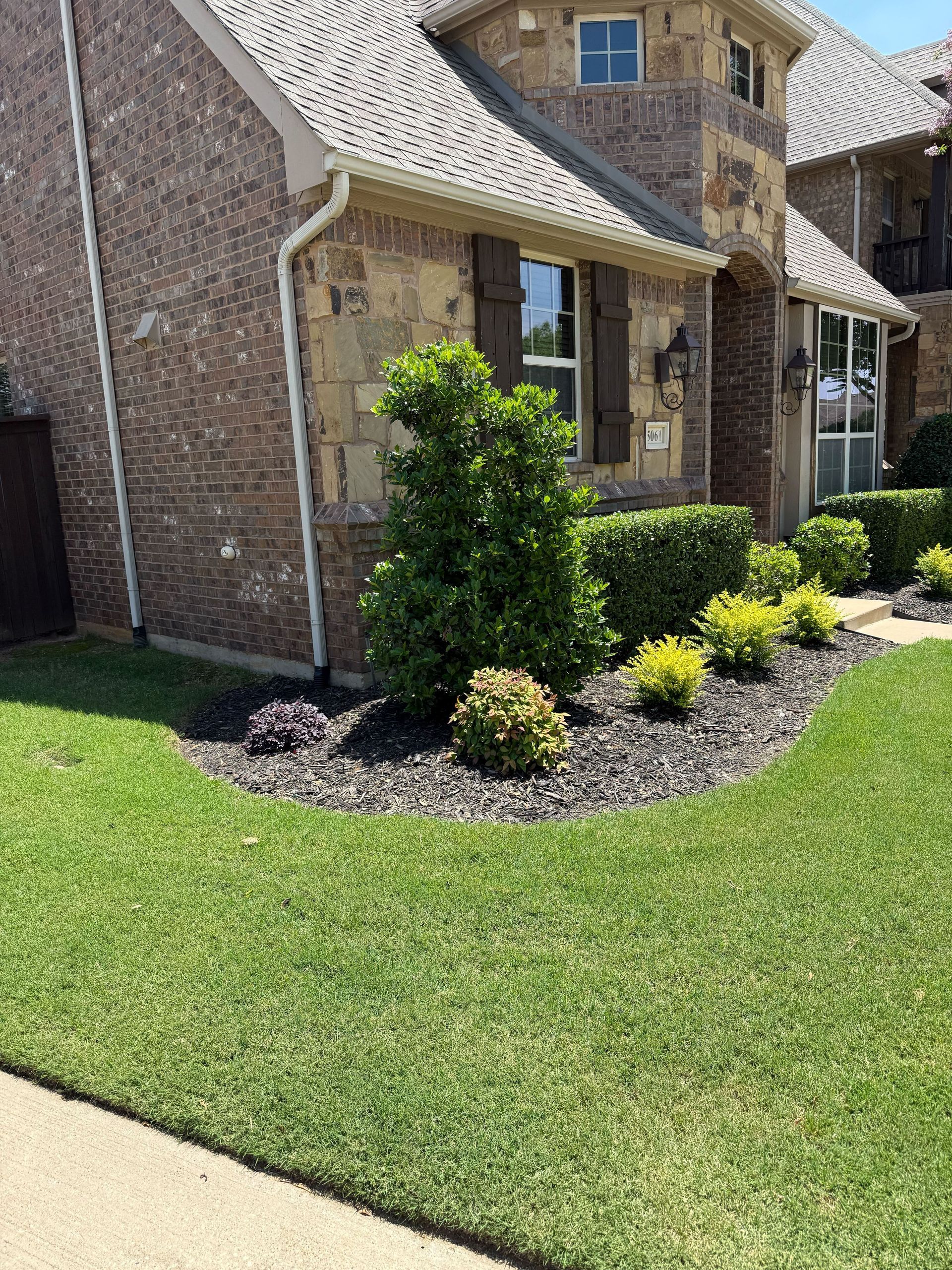 A brick house with a lush green lawn in front of it.