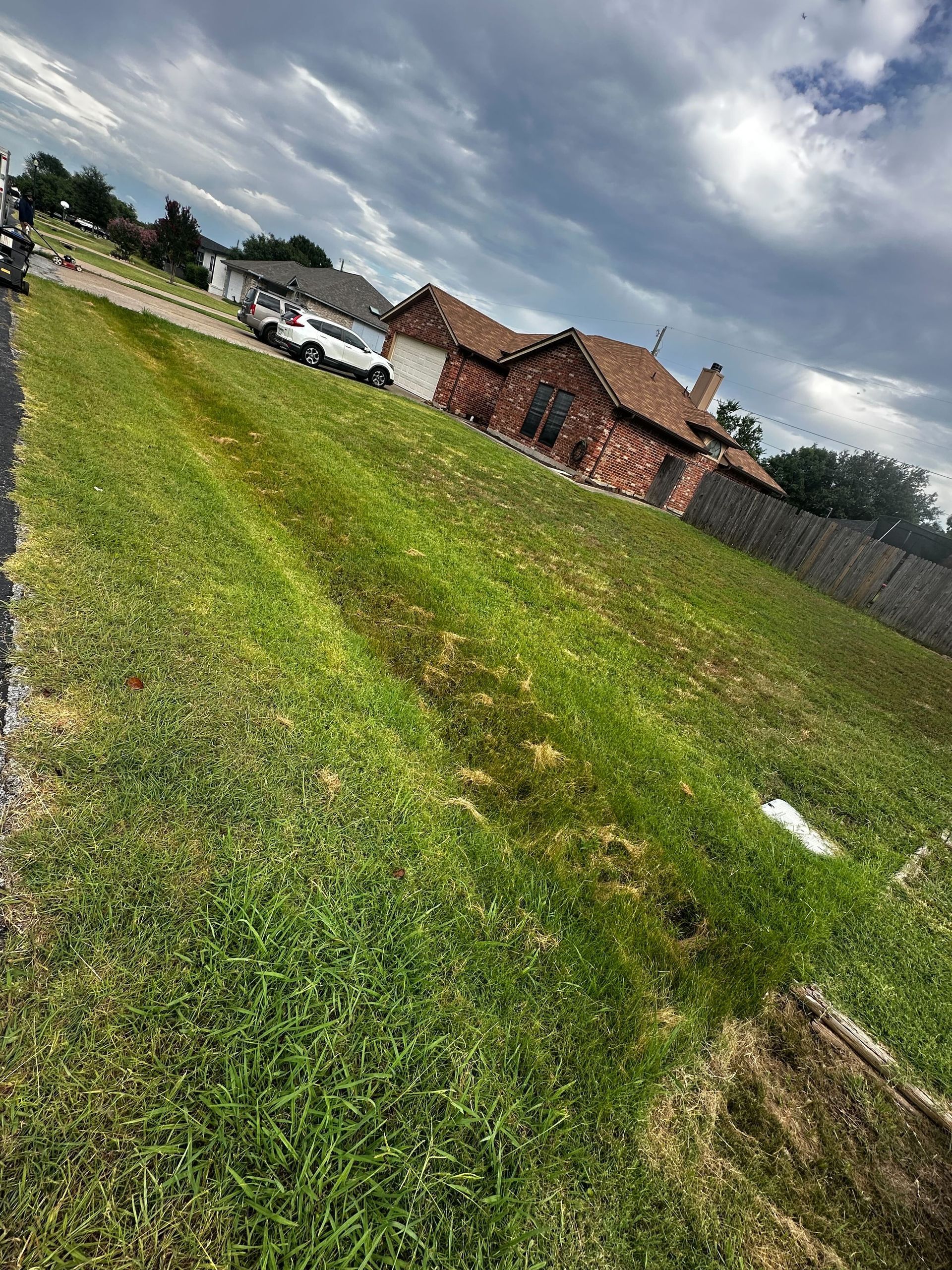 A lush green field with a brick house in the background.