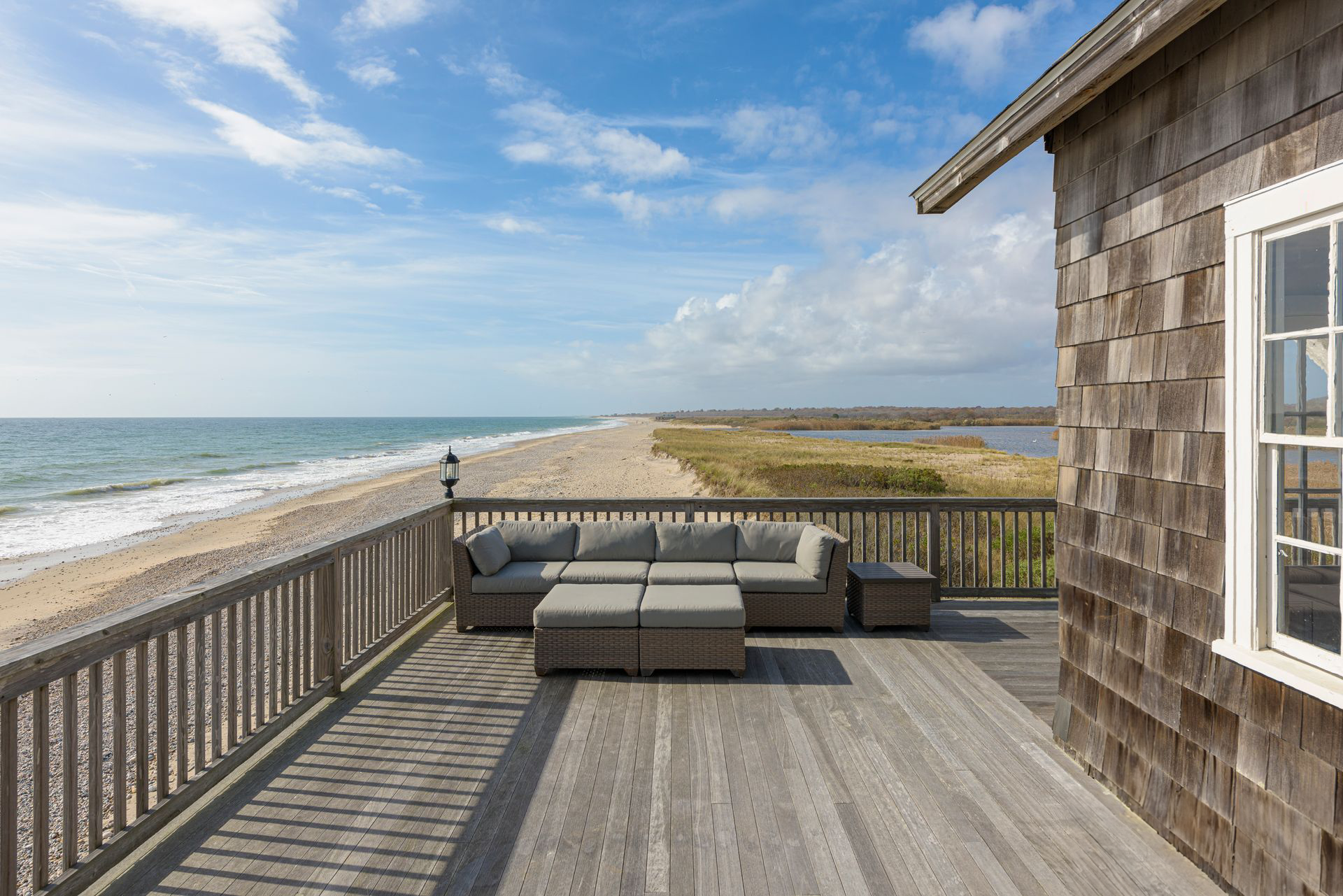A wooden deck with a couch on it overlooking the ocean.