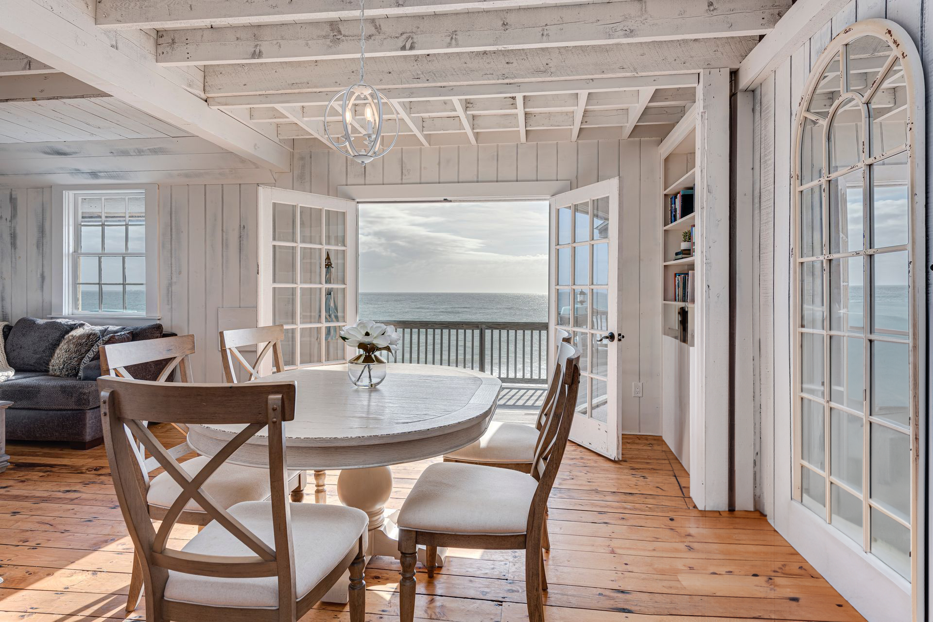 A dining room with a table and chairs and a view of the ocean