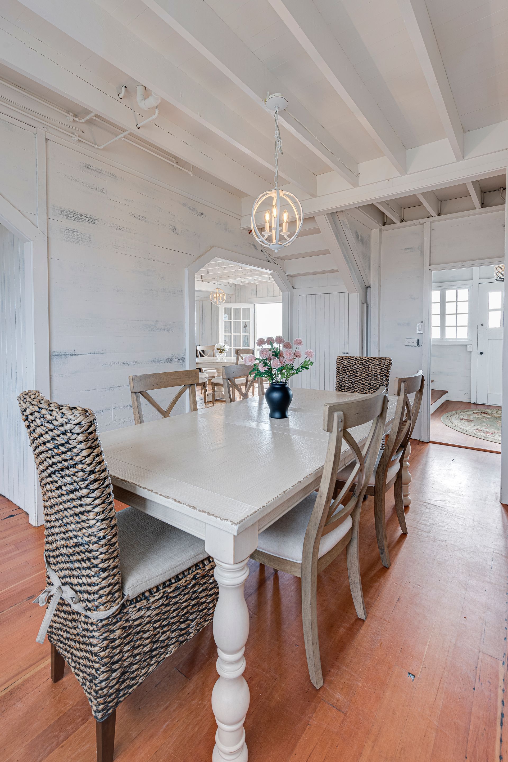 A dining room with a white table and wicker chairs