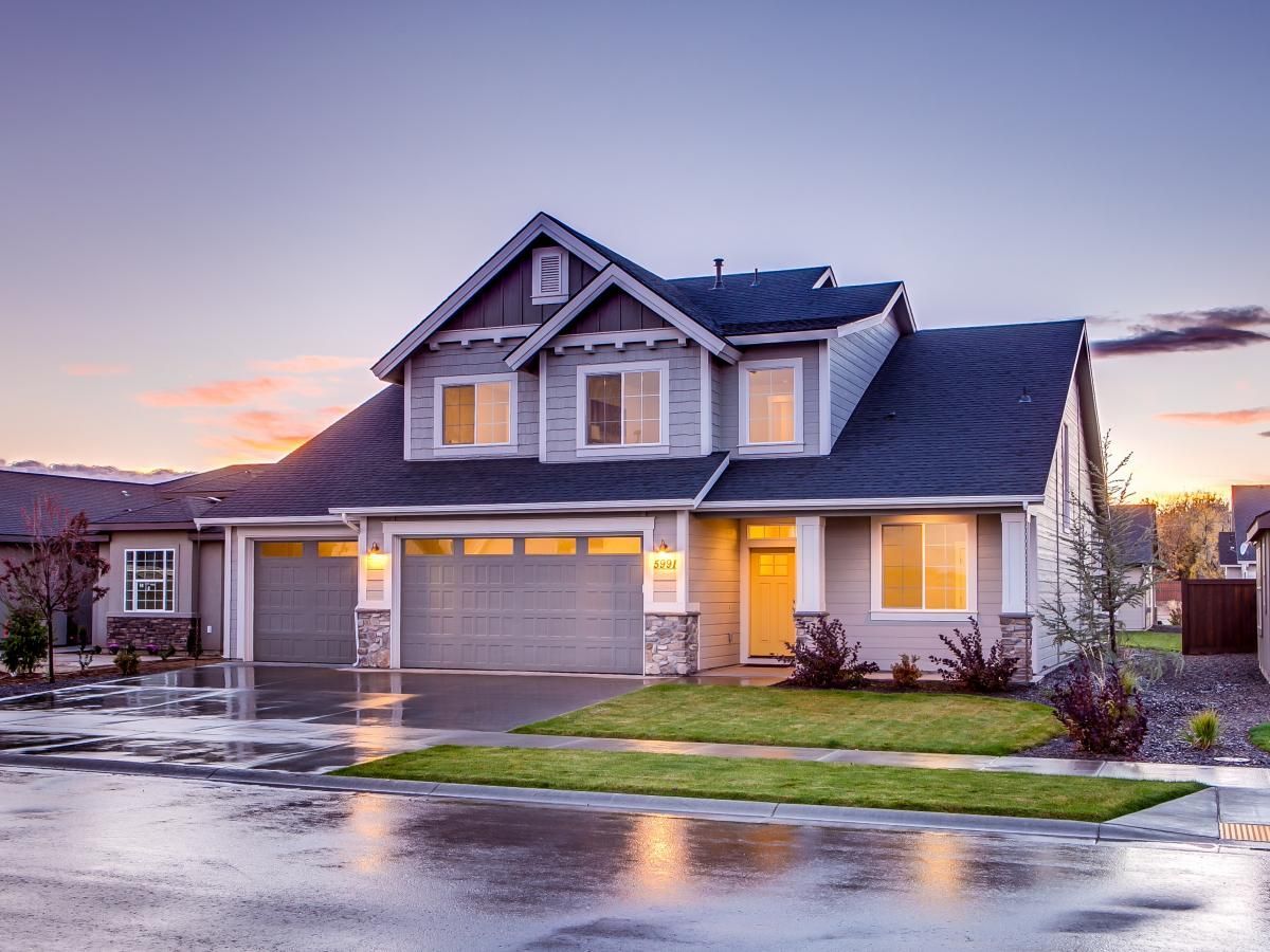 A large house with a garage and a driveway in a residential neighborhood.