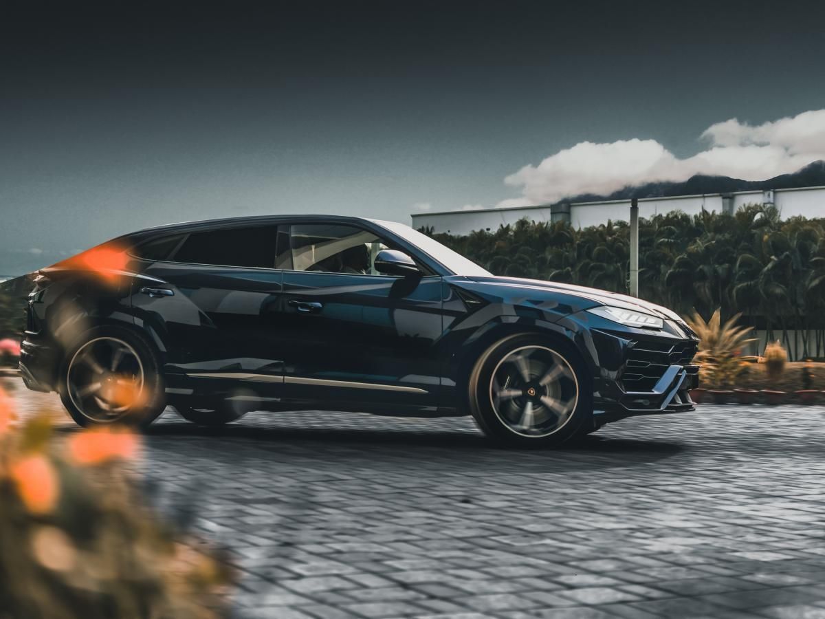 A black car is parked on a cobblestone street.