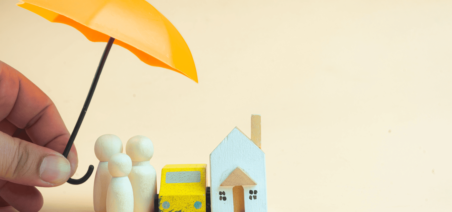 A mini umbrella sheltering mini figures of people and a house, symbolizing coverage