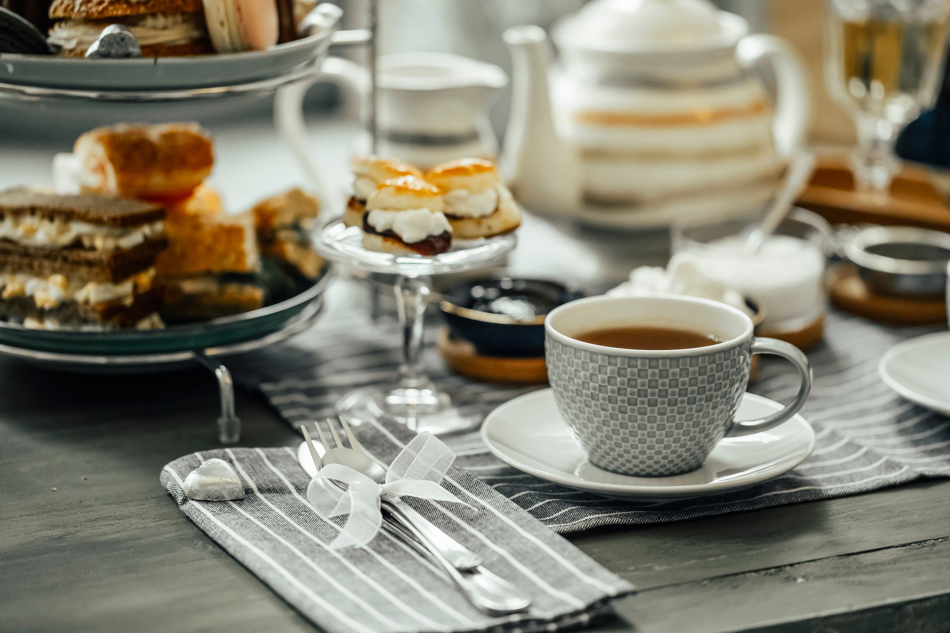 Tè pomeridiano servito su un tavolo con una tazza di tè, dolci e posate.