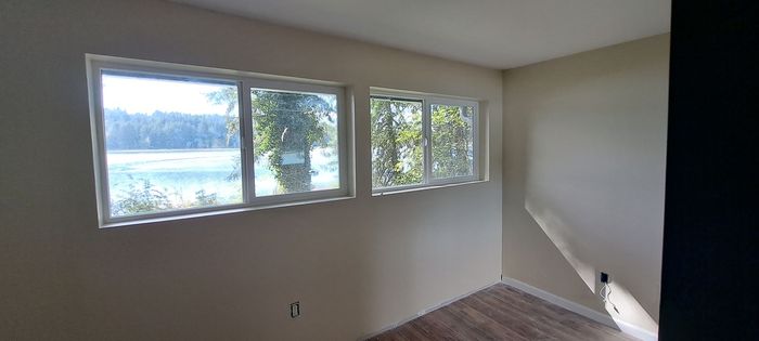 a room with three windows and a view of a lake