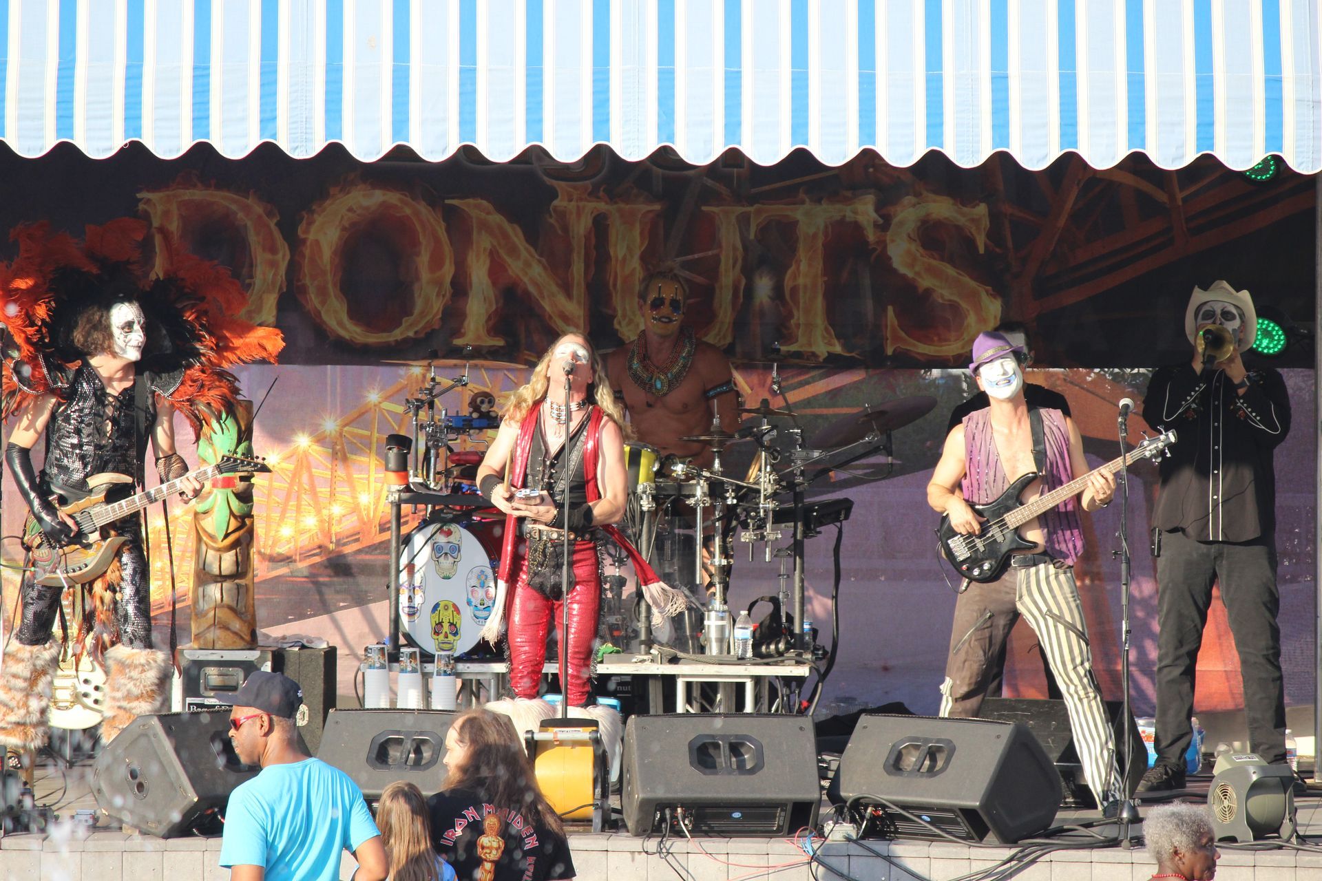 A band on stage with a sign behind them that says donuts