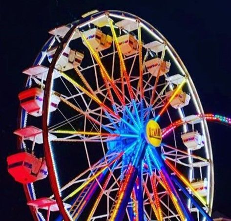 A ferris wheel at a carnival with a yellow sign that says ' Kemah ' on it