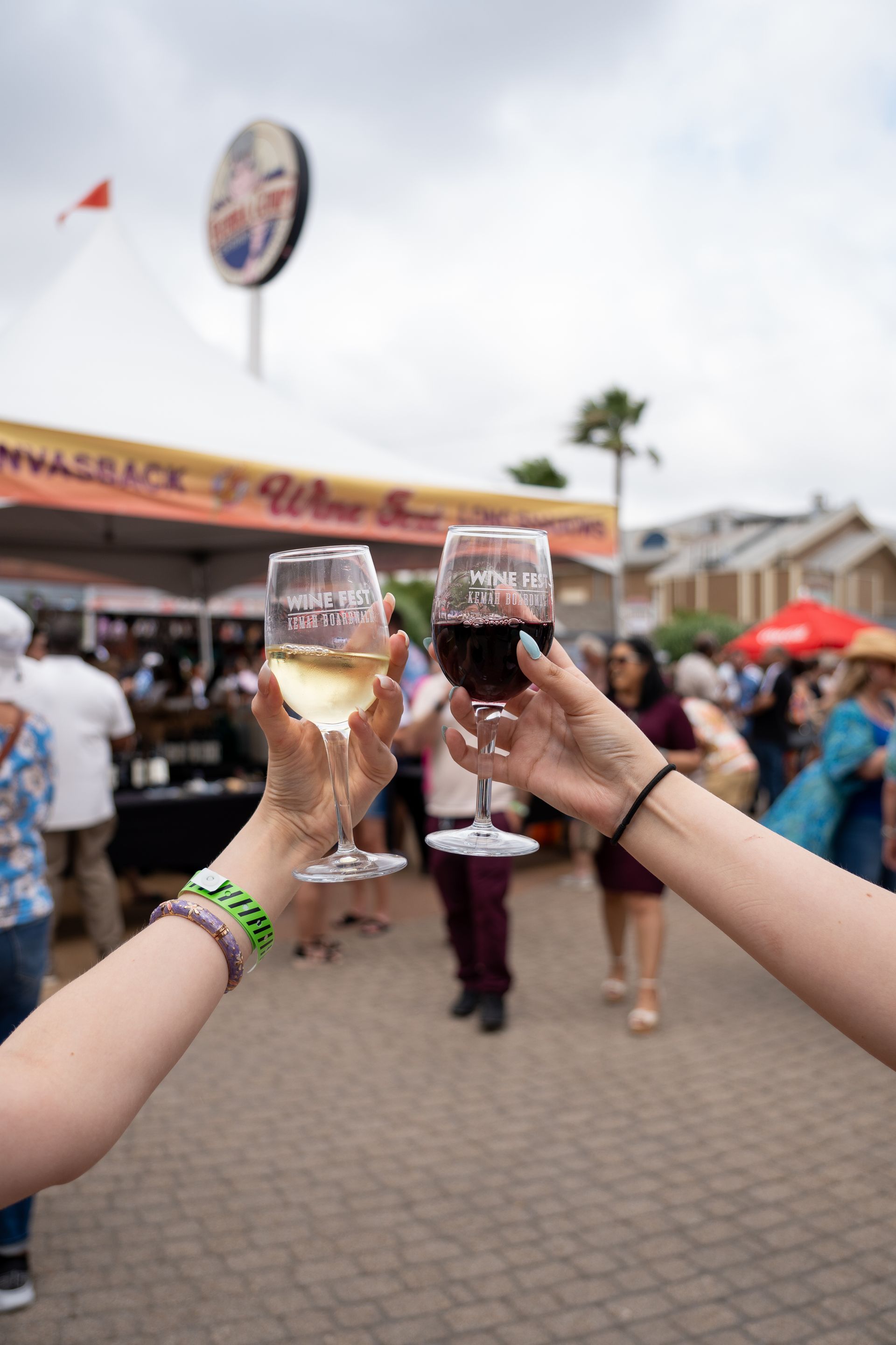 Two people toasting with wine glasses at a festival