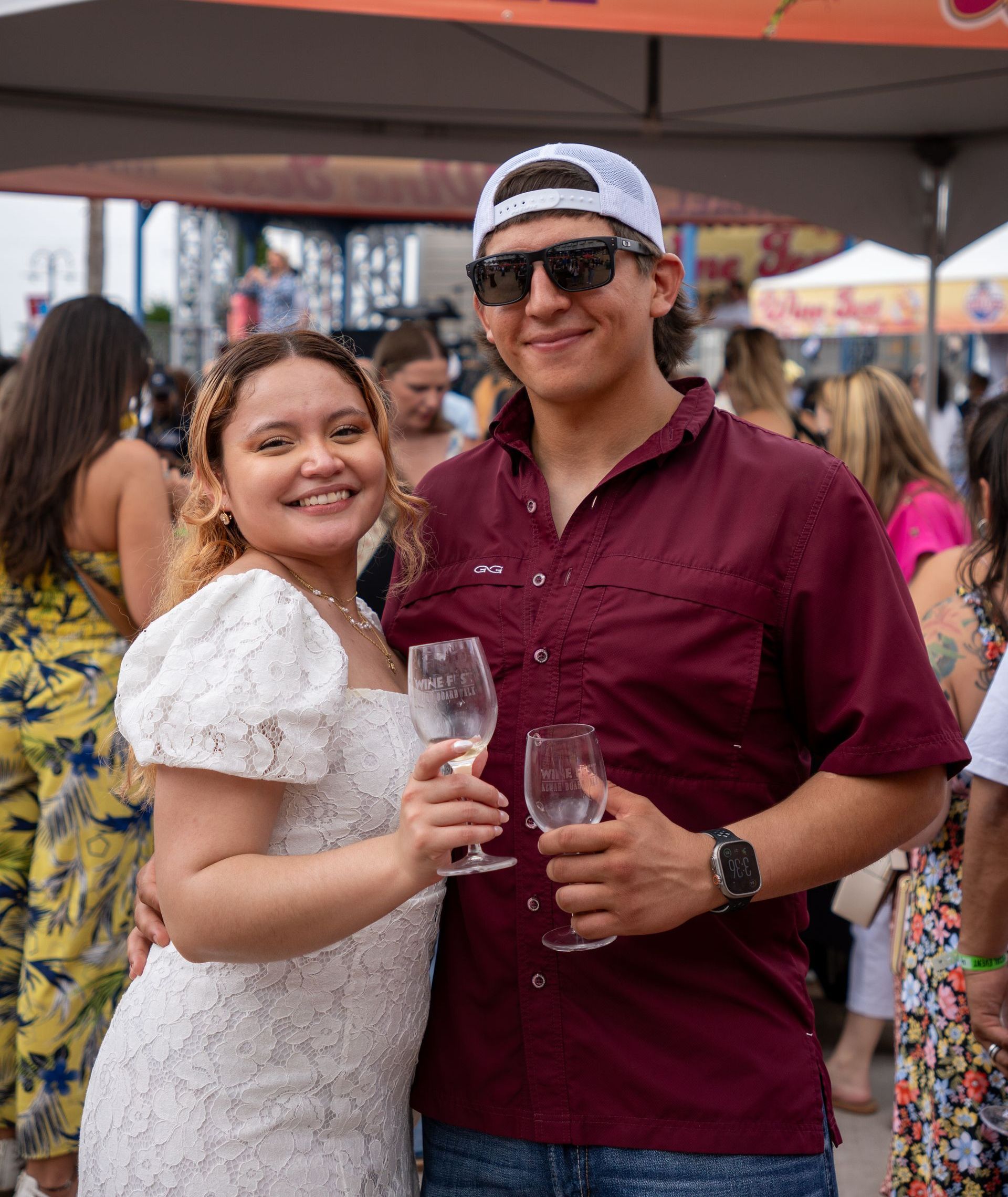 A man and a woman are posing for a picture while holding wine glasses