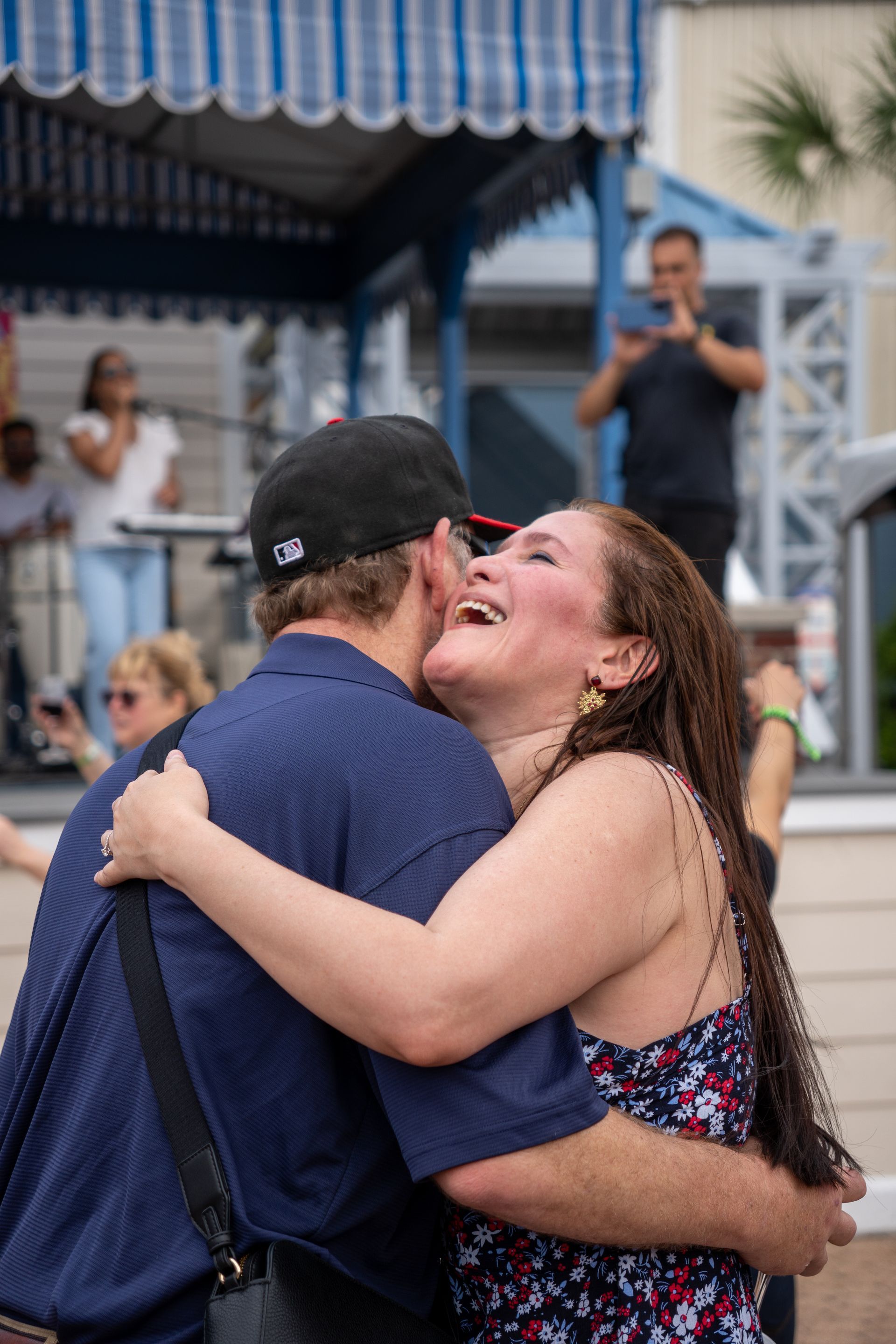 A man and woman are hugging and laughing while a man takes a picture