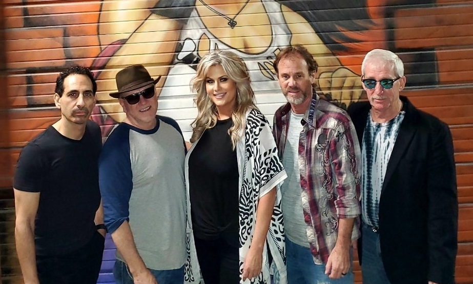 A man in a cowboy hat stands in front of a texas flag